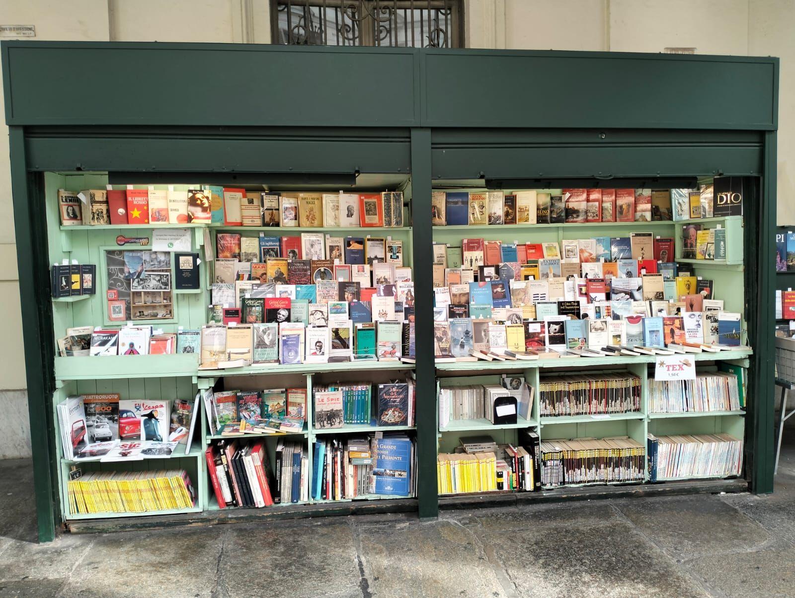 Outdoor bookstand displaying a variety of books and magazines on shelves.